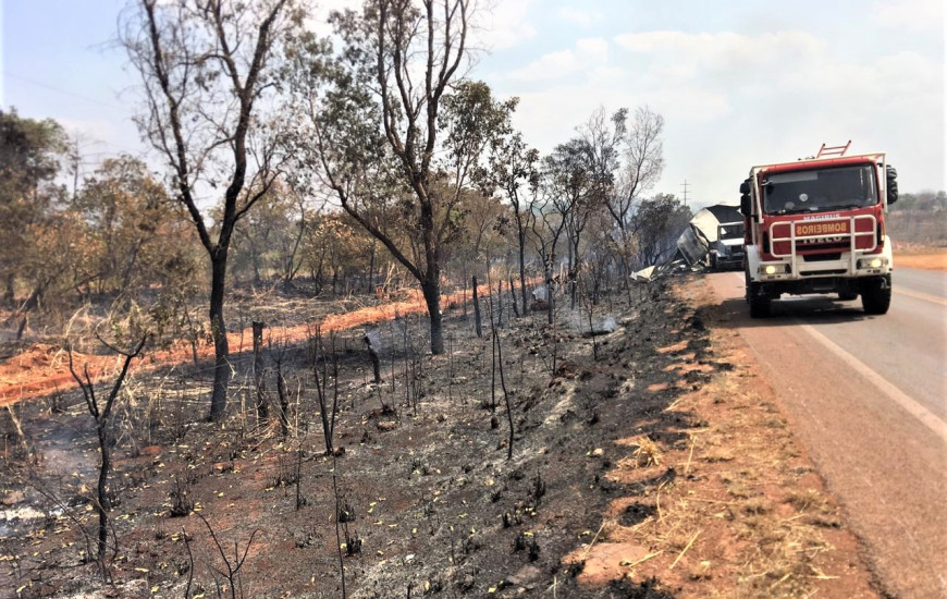 Bombeiros combatem incêndio na beira da rodovia.